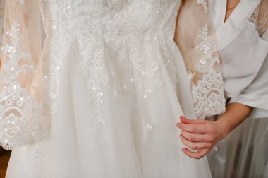 Gelin elinde bir gelinlik tutuyor. Dantelli klasik şık bir elbise. Düğün Sabahı Hazırlıkları.