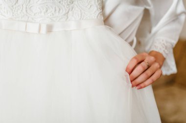 Gelin elinde bir gelinlik tutuyor. Dantelli klasik şık bir elbise. Düğün Sabahı Hazırlıkları.