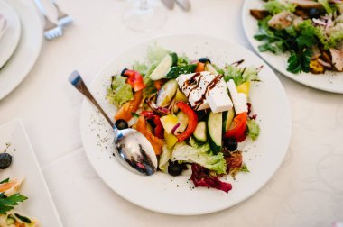 Masanın arkasında beyaz bir tabakta Yunan salatası. Kapatın. Üst görünüm.