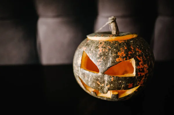 Halloween pumpkin smile and scary eyes for party night. Close up view of scary Halloween pumpkin with eyes glowing inside at black background. Selective focus.