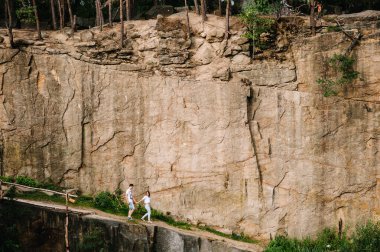 Kayaların arka planında giden kadın ve erkek. Eski bir endüstriyel granit ocağının manzarası. Kanyon. Sonbaharın doğası. Metin ve tasarım için yer.