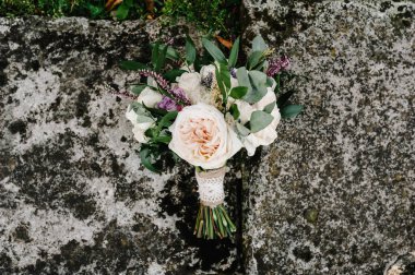 Çiçeklerden yapılmış renkli bir düğün buketi gri bir arka planda yatıyor. Gelinin caddedeki buketi. Hiç kimse. Üst görünüm.