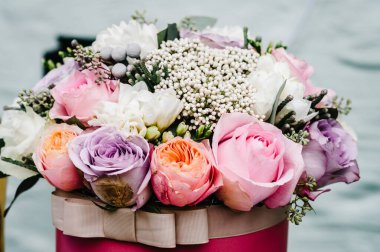 Hediye kutusunda bir buket çiçek. Beyaz, menekşe, pembe çiçekler ve yeşillik karışımı. Kapatın. Düğün dekoru.