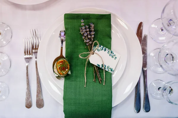 Serving guests, setting table. Two plates, silverware cutlery, green linen napkin with lavender. Wedding table decoration. flat lay. top view. Close up.