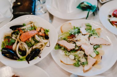 Şenlik masasında yemek servisi yapıyor. Yemek, salata, et, balık menüsü. Düğün ziyafetinde şölen masası. Dekorasyon. Ayrıntılar.