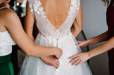 Nedime gelinin korsesini takmasına ve gelinliğini almasına yardım ediyor. Gelini düğün gününe hazırlıyor..