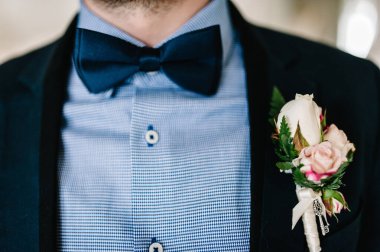 Takım elbiseli ve papyonlu adam yaklaş. Ceketin üzerinde - düğme deliği, yaka çiçeği. Evde sabah hazırlığı damadı var. Bir adamın moda fotoğrafı..