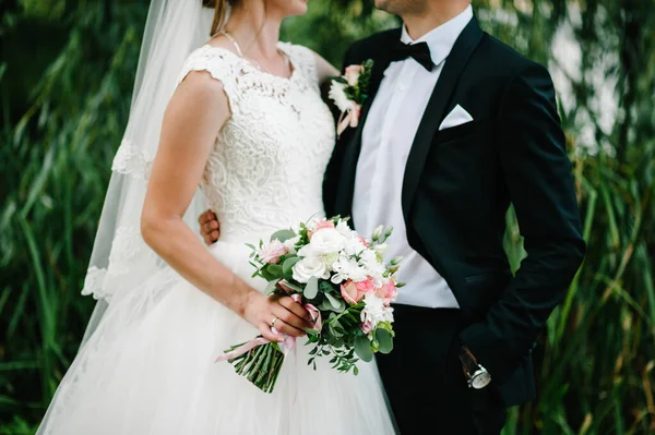 結婚式の花束を手に花嫁と新郎は 自然の裏庭で屋外の結婚式に立って — ストック写真