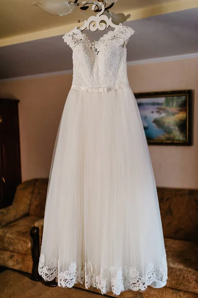 部屋のハンガーにかかって美しい古典的なレースシルクのウェディングドレス 朝の準備結婚式のコンセプト ヴィンテージウェディングドレス — ストック写真