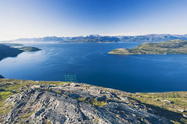 Salmon farms in Norwegian fjord,  near Alta. View from high mountain peak at sunny day.