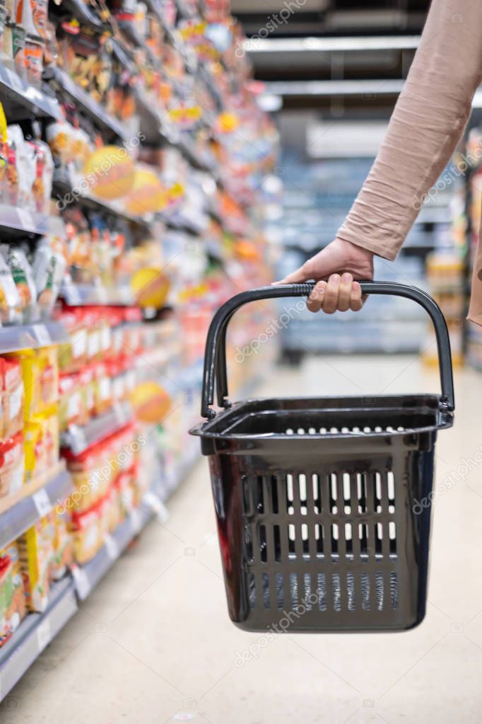 A woman is holding the empty basket in super market