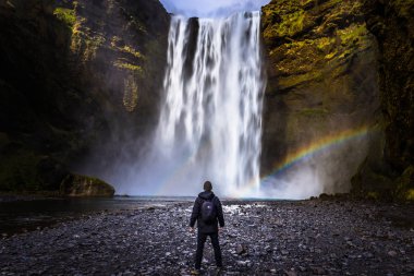 Skogafoss - May 04, 2018: Adventurer at the massive Skogafoss waterfall, Iceland clipart
