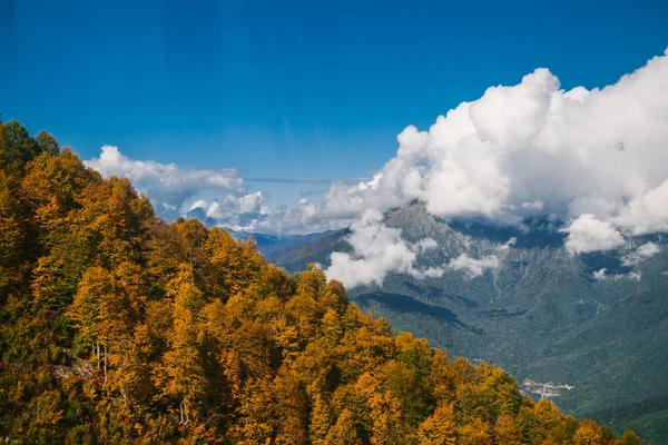 Dağlarındaki sonbahar orman çalılar ve otlar ile kaplıdır. Renkli sonbahar manzara. Sıcak sonbahar güneşli bir gün. Bulutlar dağların üzerinden