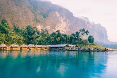 Tay tekneler şafakta. Küçük bir Tay köyün su bungalov rıhtımda tekneler. Lake Cheo Lan Tayland Ulusal Park Khao Sok. Dağlar ve bulutlar içinde belgili tanımlık geçmiş. Şafak ormanın üzerinde