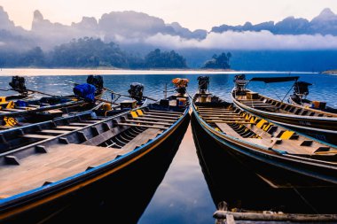  Tay tekneler şafakta. Tekneler iskelede. Lake Cheo Lan Tayland Ulusal Park Khao Sok. Dağlar ve bulutlar içinde belgili tanımlık geçmiş. Şafak ormanın üzerinde
