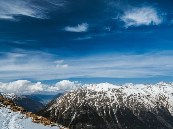 Dağ zirveleri karla kaplı. Güneşli bir günde karlı dağlar. Bulutların üzerinde dağ başında. Güzel dağ arka plan