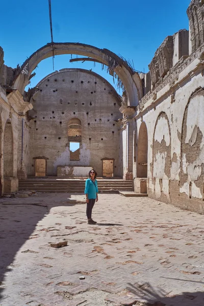 Woman watching church ruins in a village Peru.