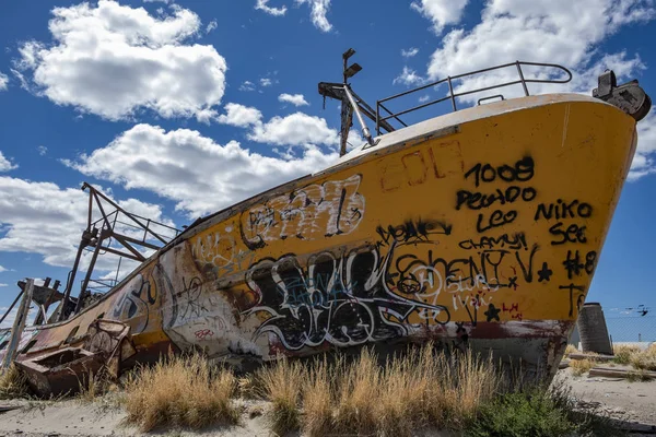 Abandoned boat encased in the coastal area with many graffiti drawn. Urban art