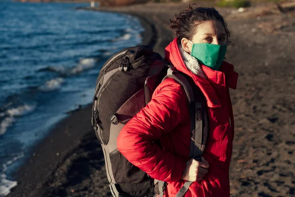 New normality for travel: Woman with backpack wearing protective mask to avoid contagion