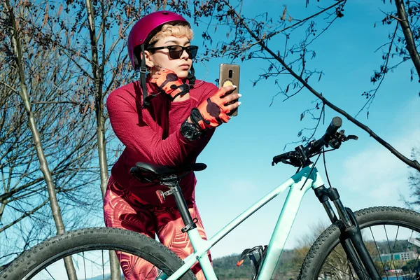 Young woman with bike helmet and sunglasses makes selfie in a natural park
