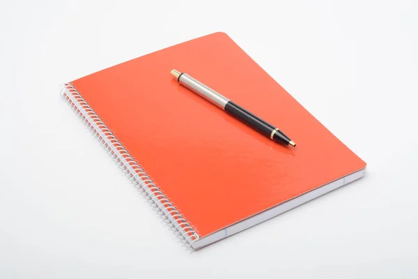 Orange notebook and pen on white background