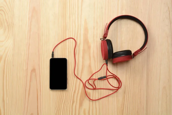 Telefone e fone de ouvido no chão de madeira — Fotografia de Stock