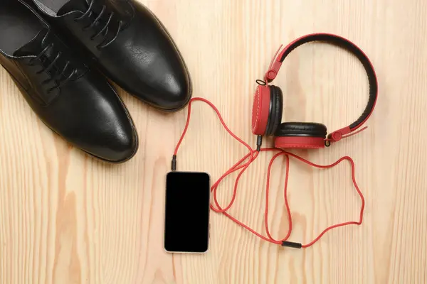 Telefone, fones de ouvido e sapatos no chão — Fotografia de Stock