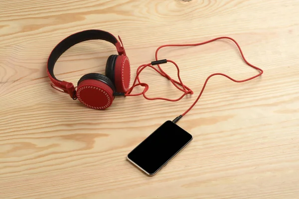 Telefone e fone de ouvido no chão de madeira — Fotografia de Stock