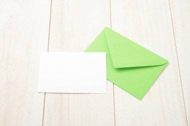 Yeşil zarf ve beyaz tahta masada boş kart.