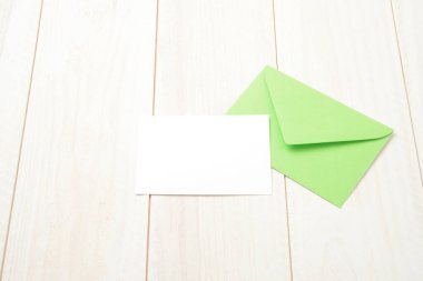 Yeşil zarf ve beyaz tahta masada boş kart.