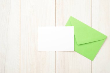 Yeşil zarf ve beyaz tahta masada boş kart.