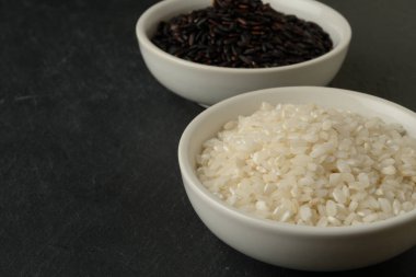 Farklı renkte iki beyaz kase, siyah ve beyaz yuvarlak taş arka plan, üst manzara.