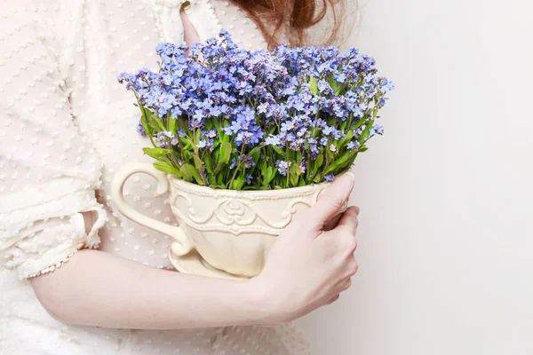 Woman holding a pot with forget-me-not flowers. Spring decoration idea.