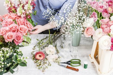 Çiçekçi iş yeri: kadın bir buket gül, matthiolas, tipik çiçekler ve gypsophila paniculata dallar ile düzenleme.