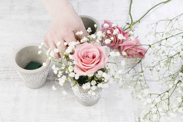 Florist at work: woman making decorations with pink roses and white gypsophila paniculata. Step by step, tutorial.