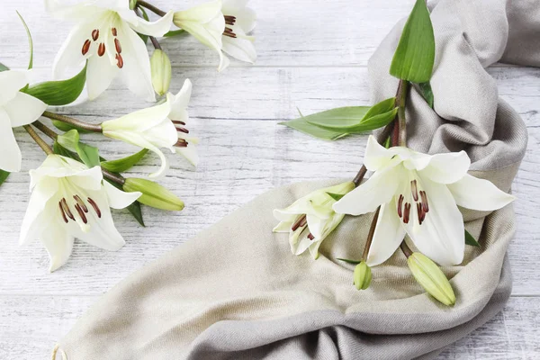 Witte lelies en groene sjaal op houten achtergrond. — Stockfoto