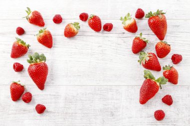 Beyaz ahşap arka planda çilek ve ahududu.