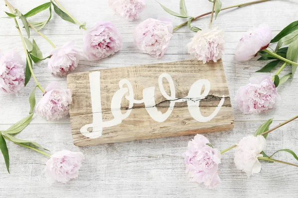 Letras de amor escritas a mano sobre fondo de madera y peonías rosadas —  Fotos de Stock