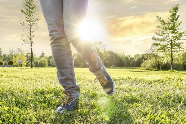 Joven usando zapatillas de deporte, caminando sobre la hierba durante beaut — Foto de Stock