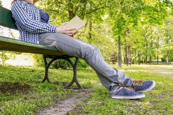 Donna che legge un libro, seduta sulla panchina in un parco — Foto Stock