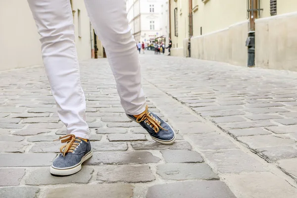 Joven con zapatillas, caminando por la calle empedrada . — Foto de Stock