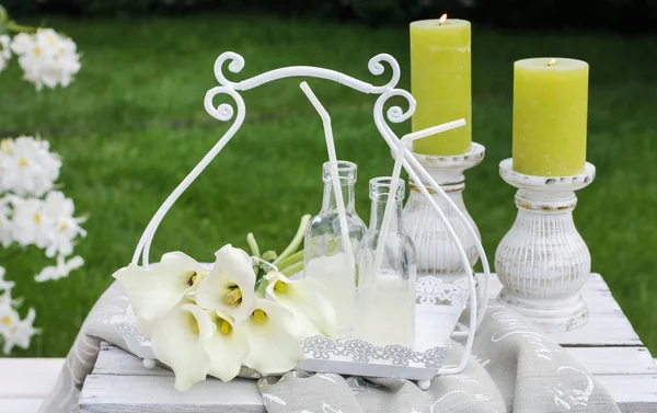 Bottles with lemonade, scented candles and calla flowers in the — Stock Photo, Image