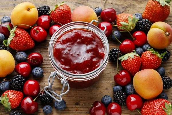 Jar of strawberry jams among summer and autumn fruits on a woode — Stock Photo, Image