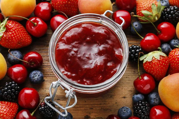 Jar of strawberry jams among summer and autumn fruits on a woode — Stock Photo, Image