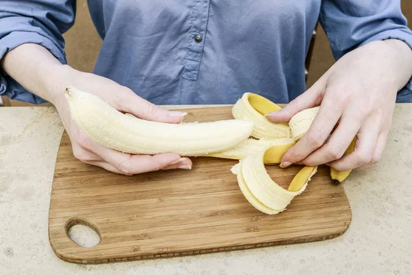 Женщина чистит банан — стоковое фото