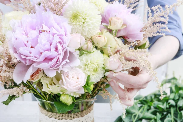 Floristin bei der Arbeit: Frau arrangiert Strauß mit rosa Pfingstrosen, Rose — Stockfoto