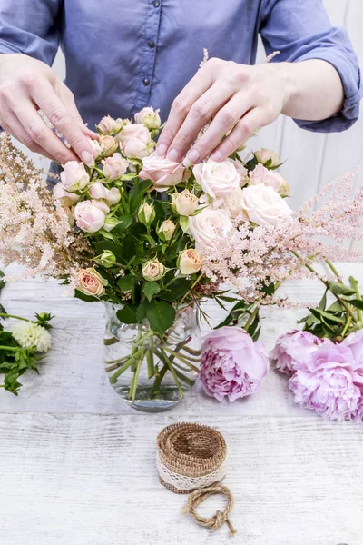 Frau arrangiert Strauß mit rosa Pfingstrosen, Rosen und gelben Dahlien — Stockfoto
