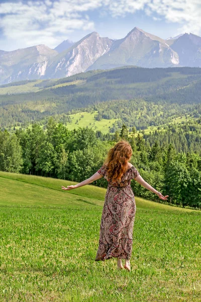 Jonge vrouw dansen op blote voeten op gras, alpine landschap. — Stockfoto