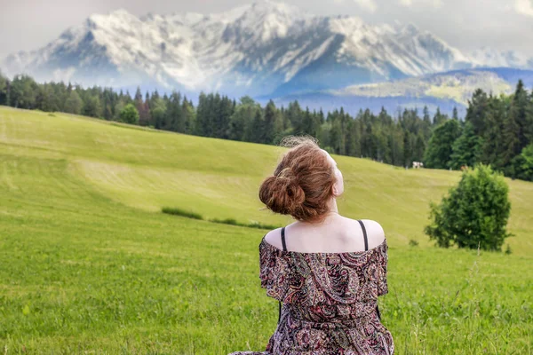 Jonge vrouw zittend op gras, alpine landschap. — Stockfoto