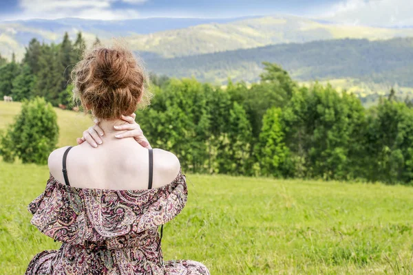 Jonge vrouw zittend op gras, alpine landschap. — Stockfoto